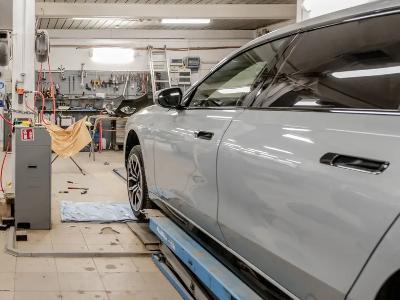 Graues Auto auf einer Hebebühne in einer Kfz-Werkstatt, im Hintergrund die Werkzeugwand